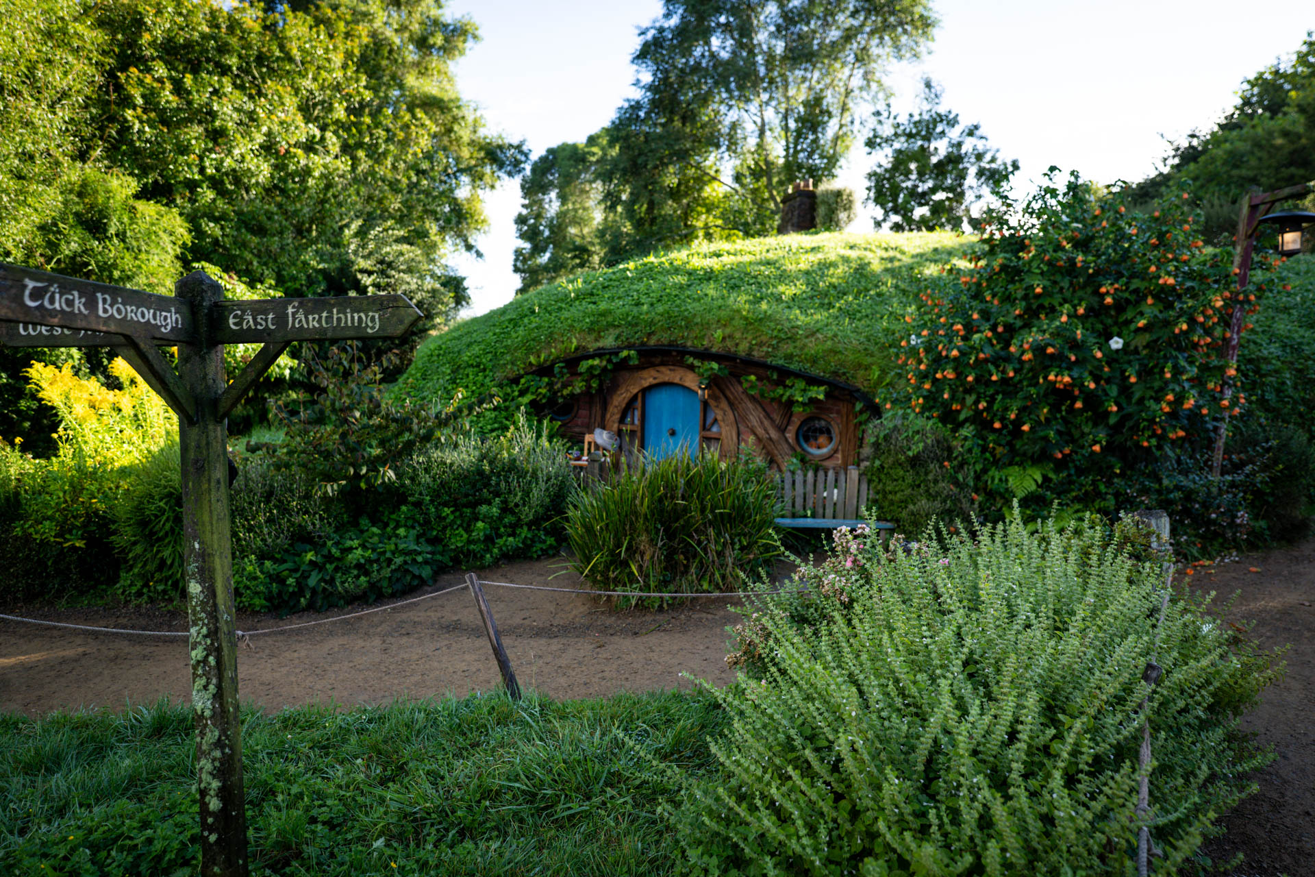 A hobbit hole door at the Hobbiton Movie Set with a signpost in front, Matamata, New Zealand